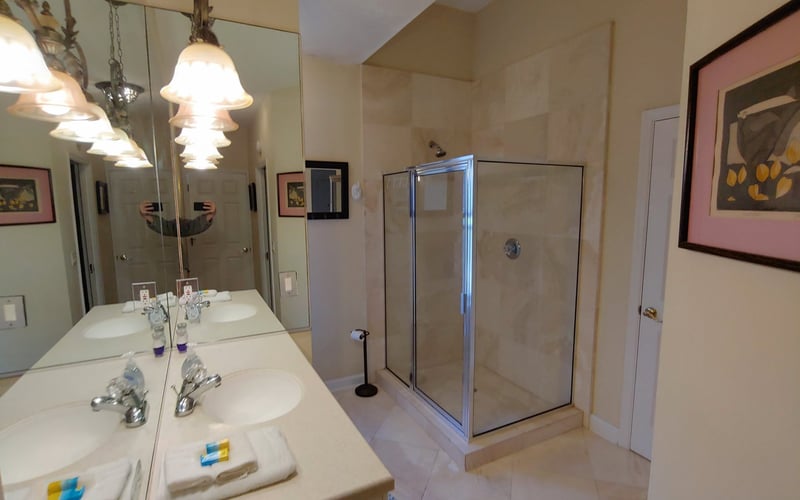 Master bathroom with double vanity, large mirror, pendant lights, and glass-enclosed shower stall